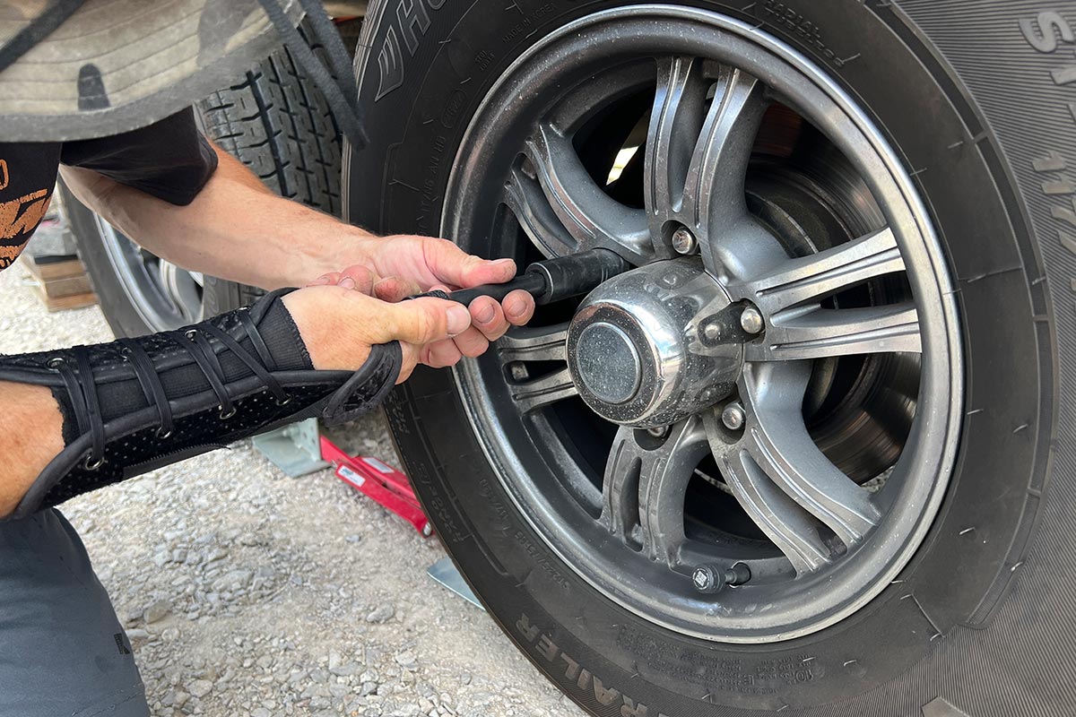 a new lug nut is threaded on to the stud by hand, using a socket and extension