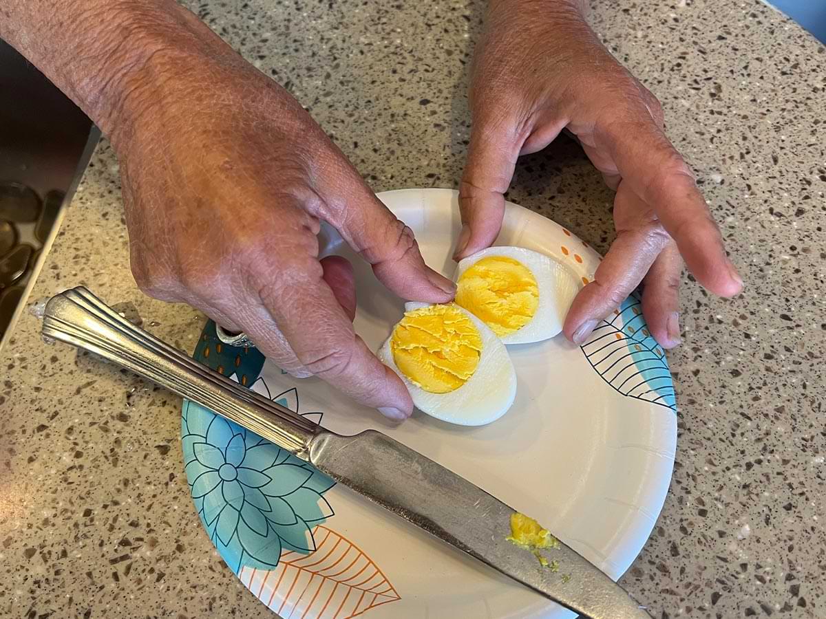 hands hold two halves of a perfectly cooked boiled egg