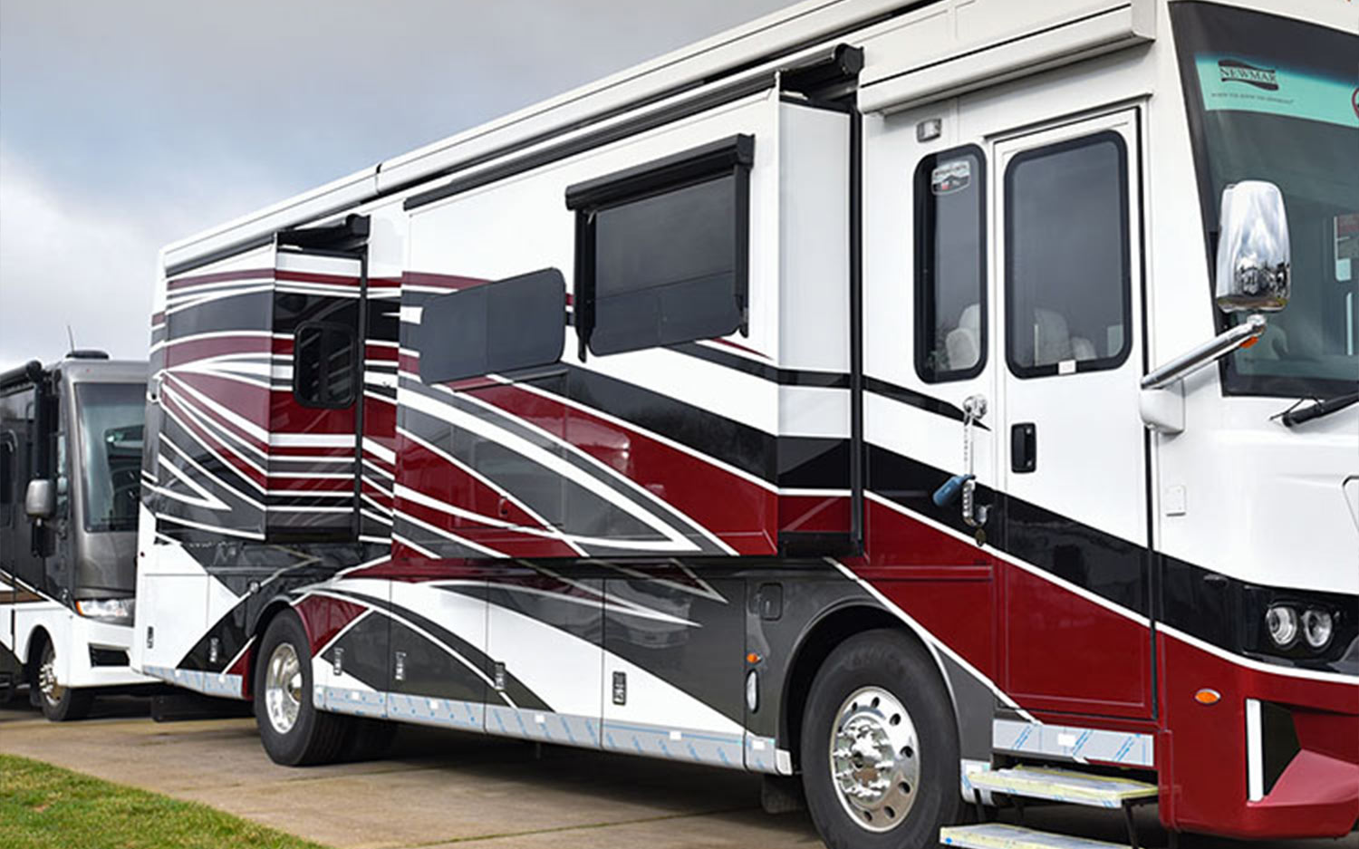 3/4ths view of a white, red and black RV with two sliderooms