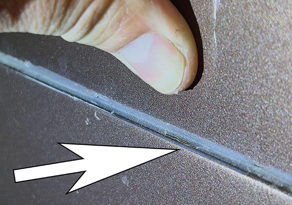 close up of a finger applying light pressure to reveal an RV's lap seal separation