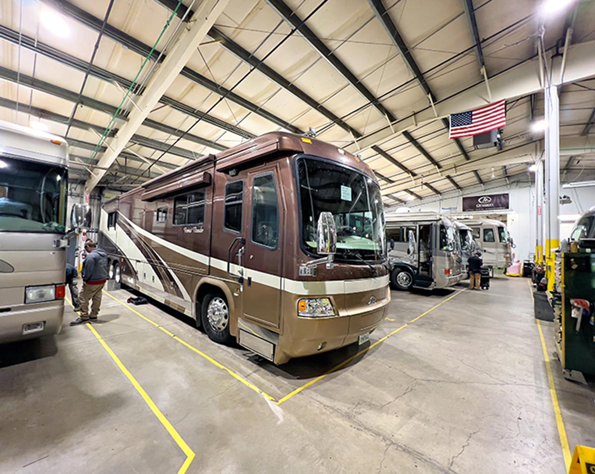 3/4ths view of a brown and gold RV parked in an RV garage