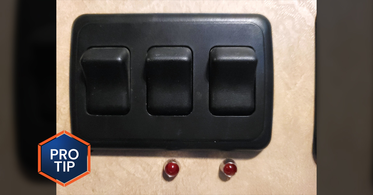 close view of a light switch with three toggles, the right two with inactive red indicator lights below