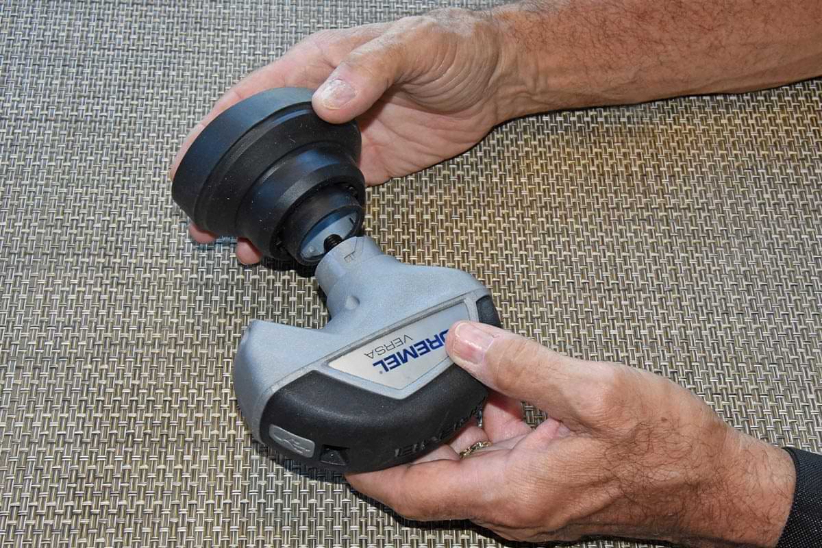 a hand removes the rubber splash guard attachment from the Dremel Versa device
