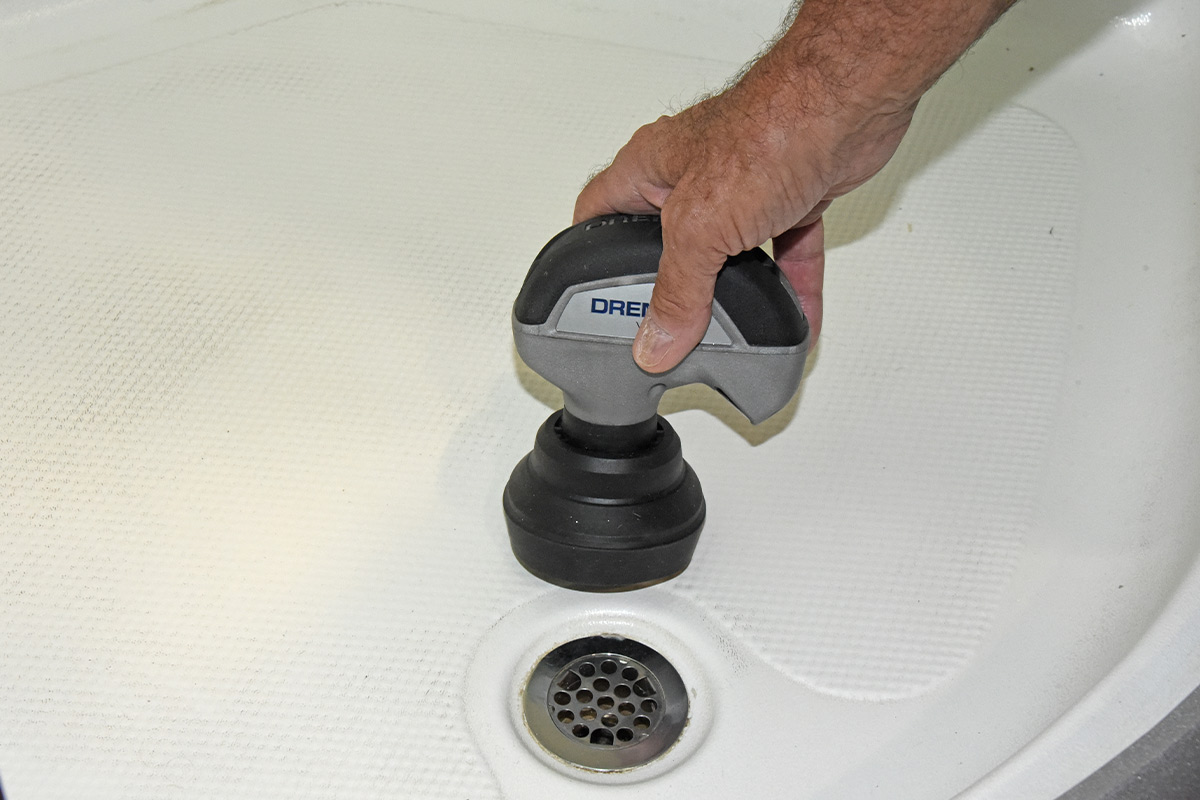 the Dremel Versa, with the splash guard attached, held to the floor of and RV shower