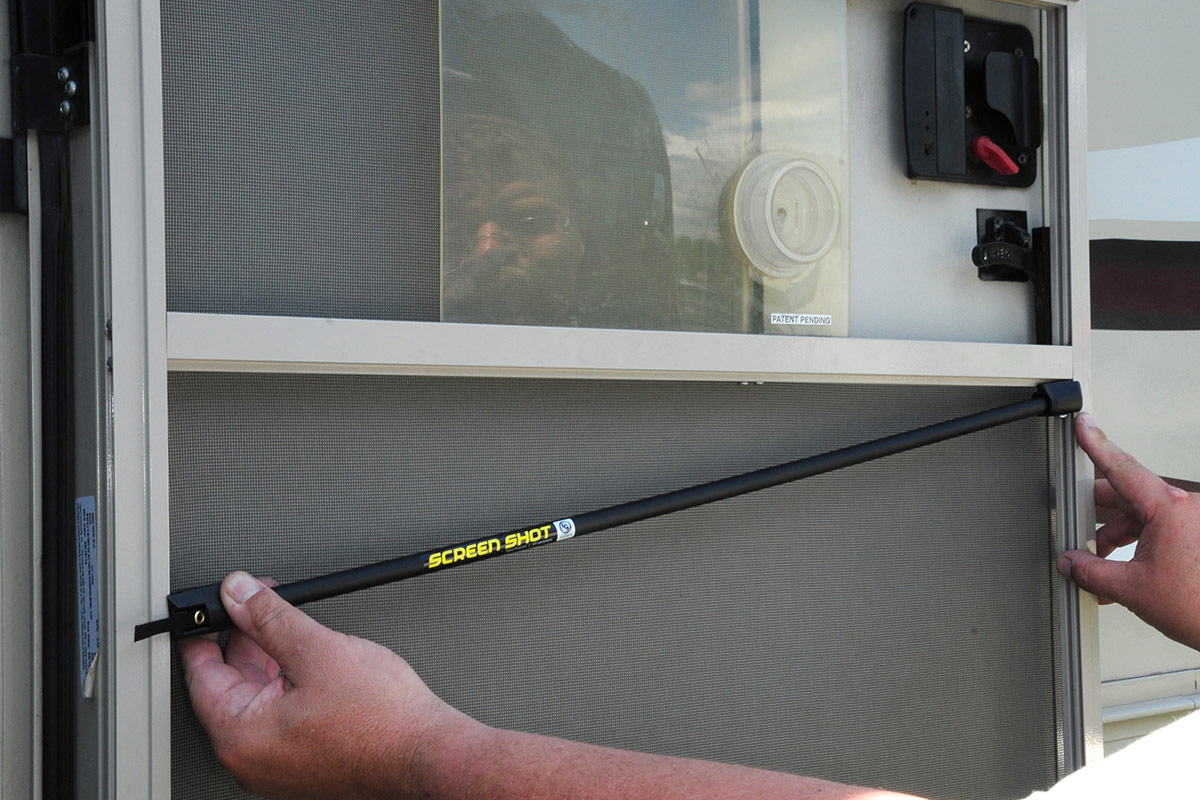 latch-side support is held in place against the screen door frame while the other side is positioned on the opposite side