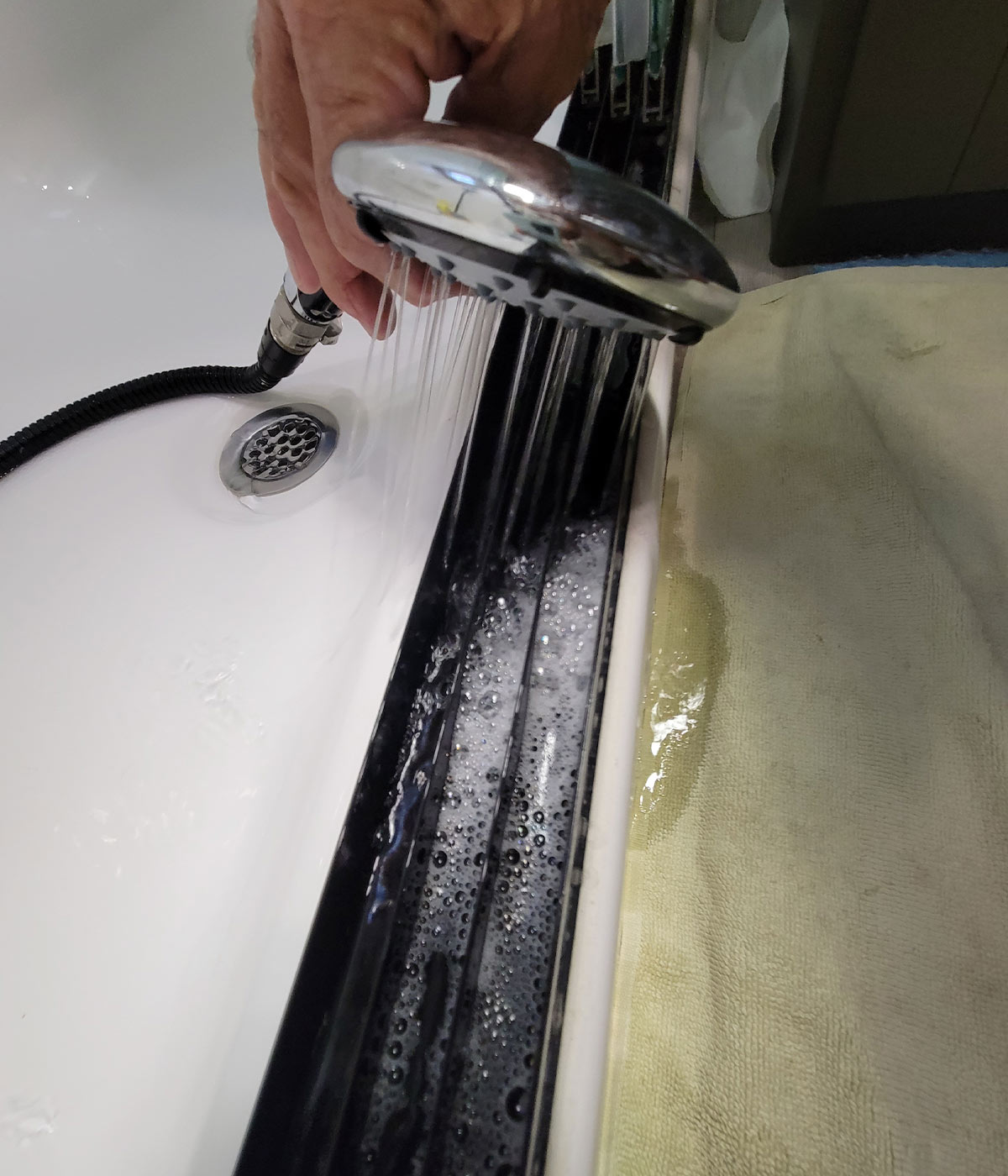 the RV shower head is used to rinse the cleaning solution and debris from the shower tracks, causing a slight spill