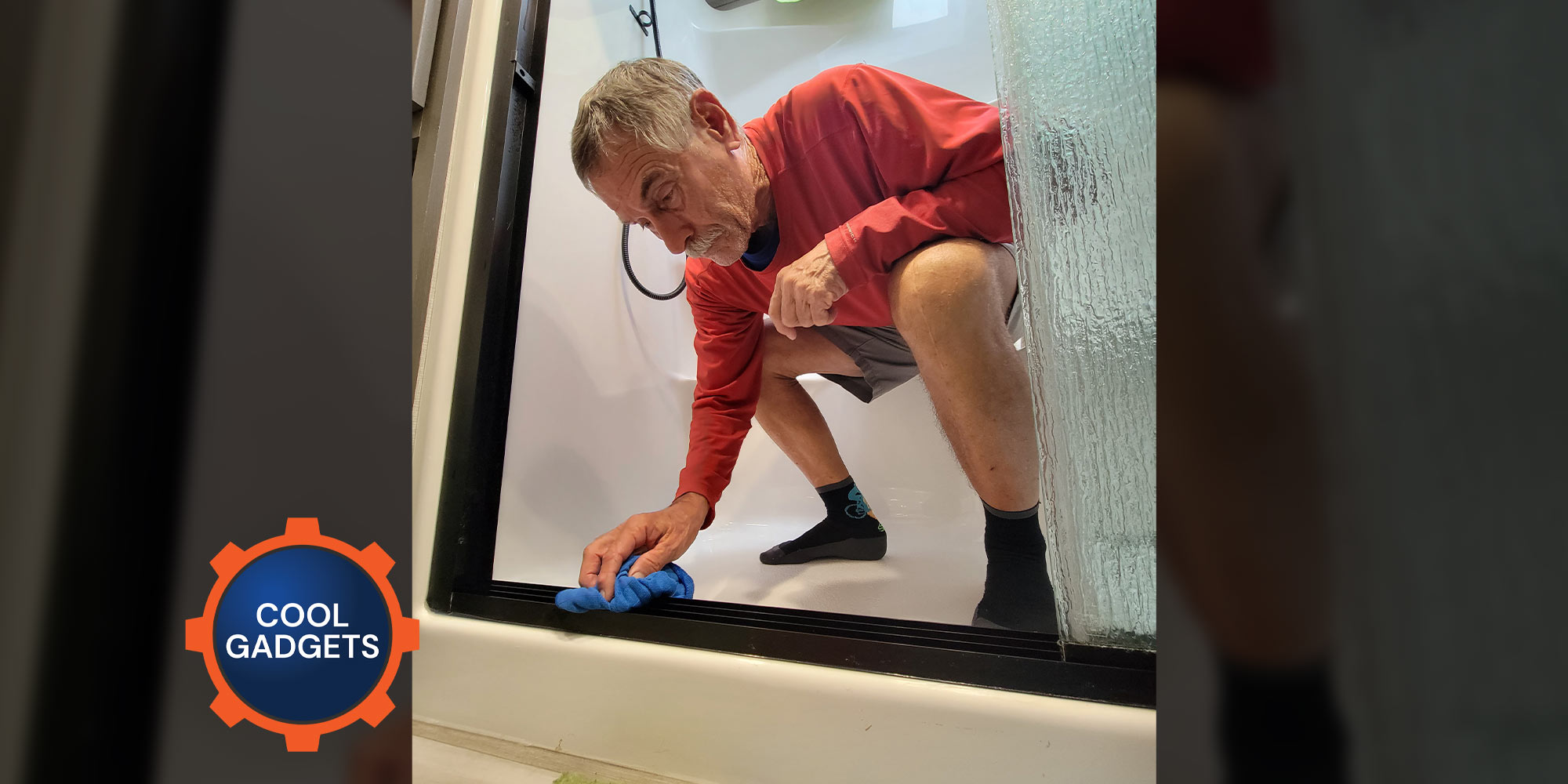 a man crouchs while inside an RV shower, using a microfiber towel to wipe the shower's sliding door tracks