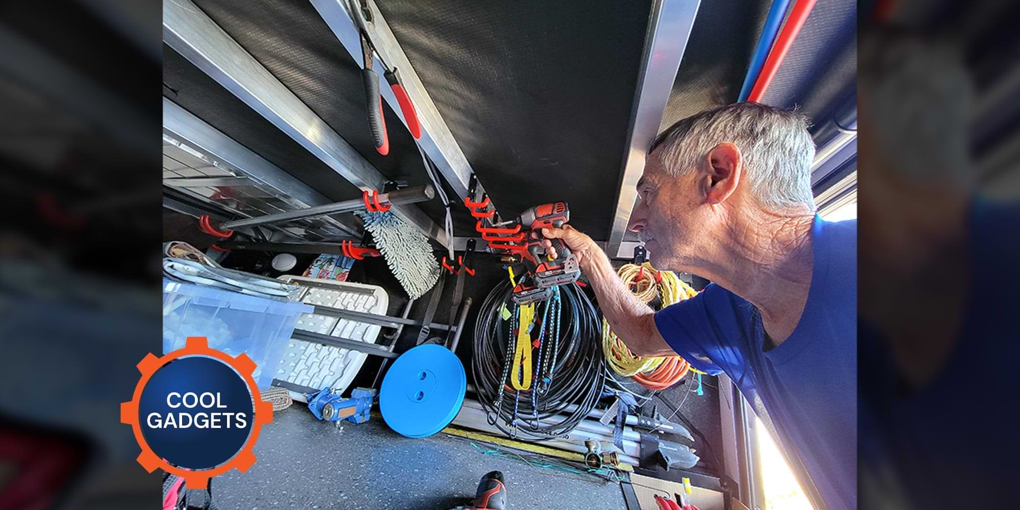 a man leaning into a deep RV external compartment uses a drill to secure a screw on a newly mounted hook