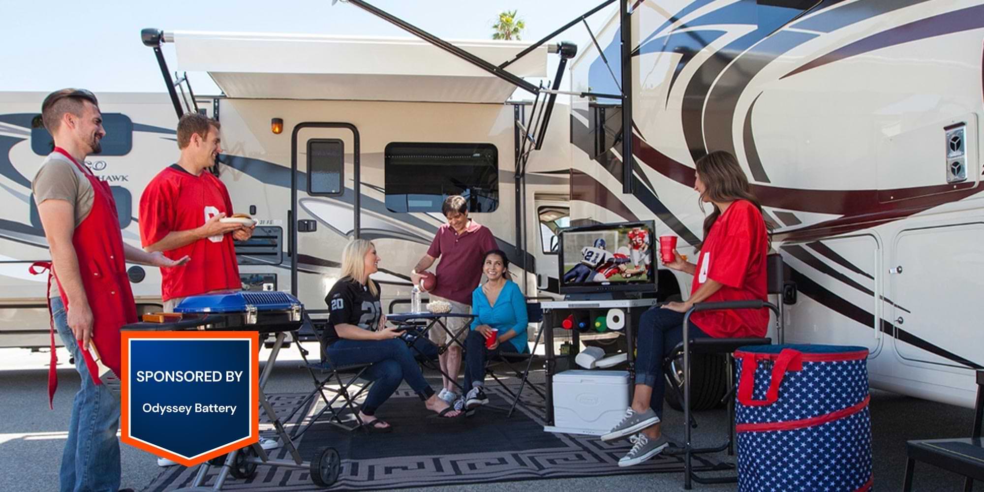 a group of people enjoy a football game on a portable television while grilling and relaxing in front of two camped RVs