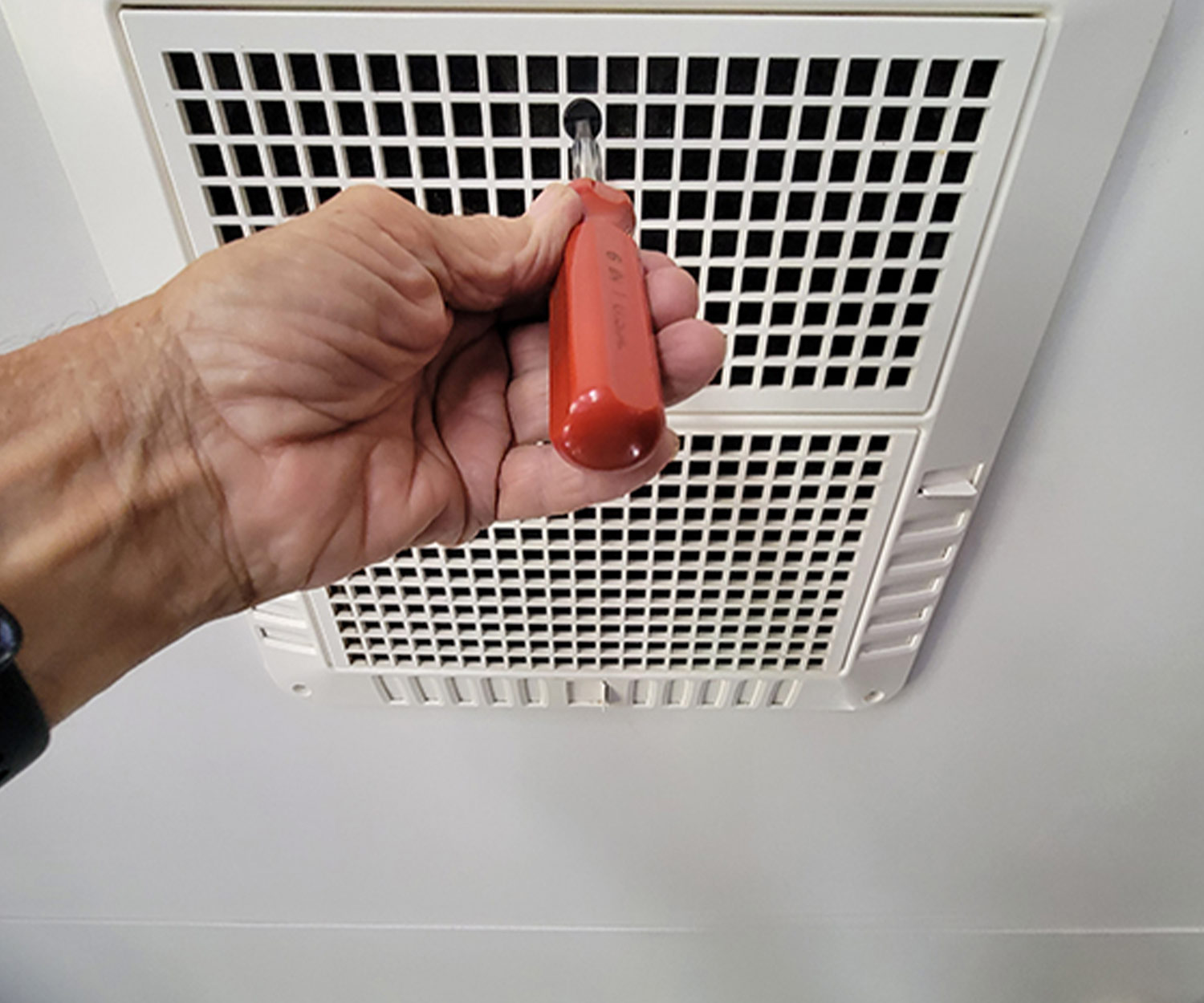 a screw driver is used to remove a screw from the AC hold-down panel