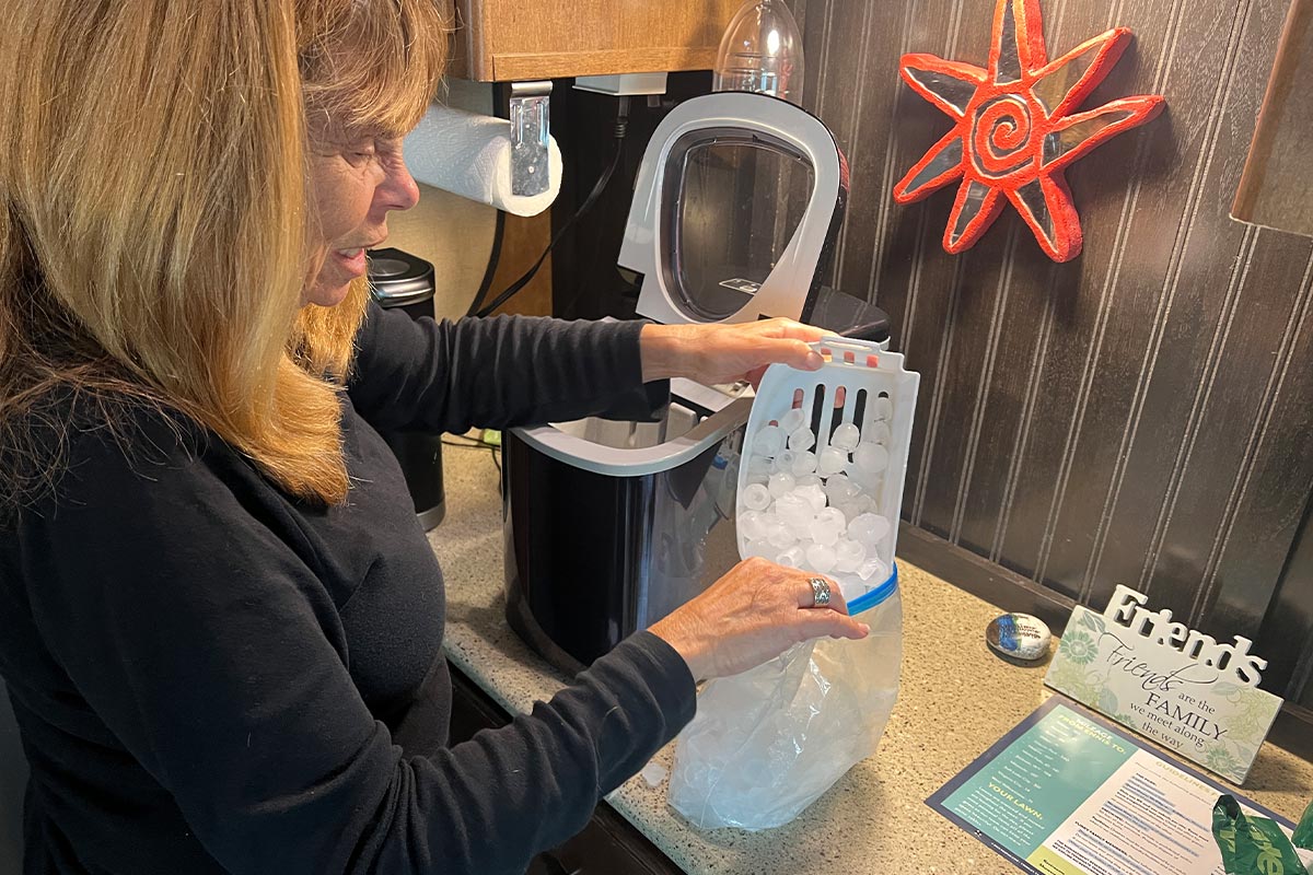 a woman pours ice from a small tray into a Ziplock bag