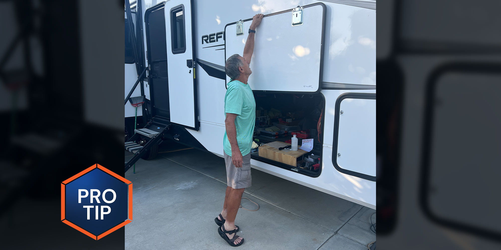 a man stands on the balls of his feet, reaching overhead to close an external compartment door on an RV