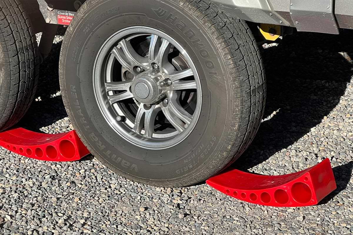 view of two RV tires touching the the thin ends of two Andersen Camper Levelers between the tire tread and the ground
