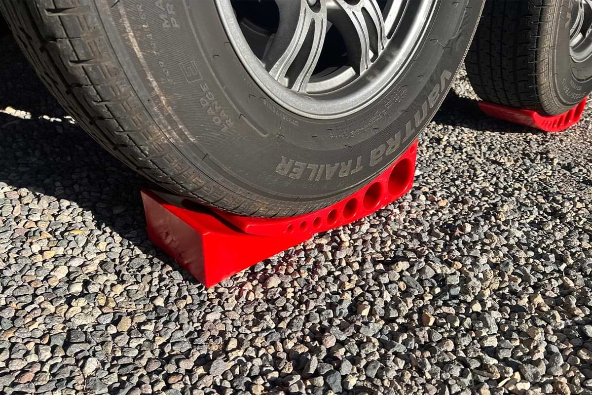 an RV tire with an Andersen Camper Leveler and a chock placed under, the thin end of the chock beneath the thin end of the leveler
