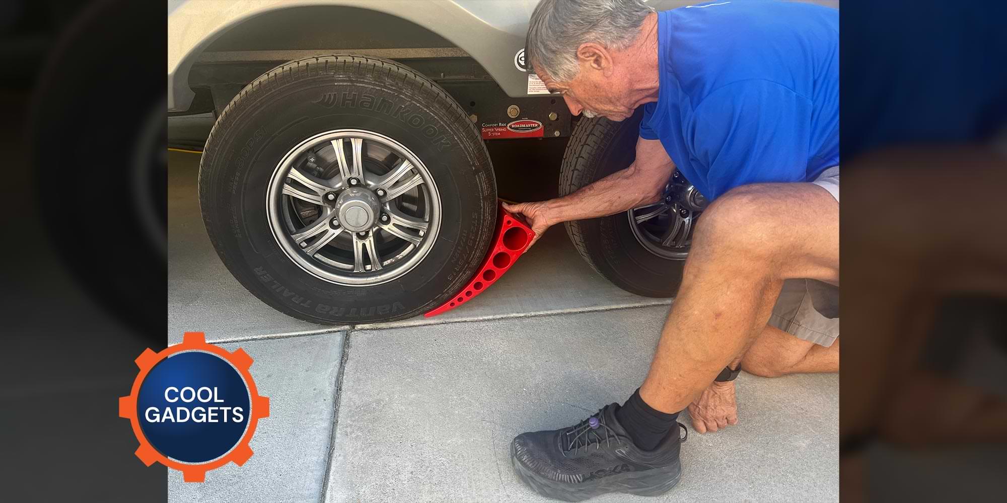 a man places a large red thorn shaped gadget beneath a tire on an RV