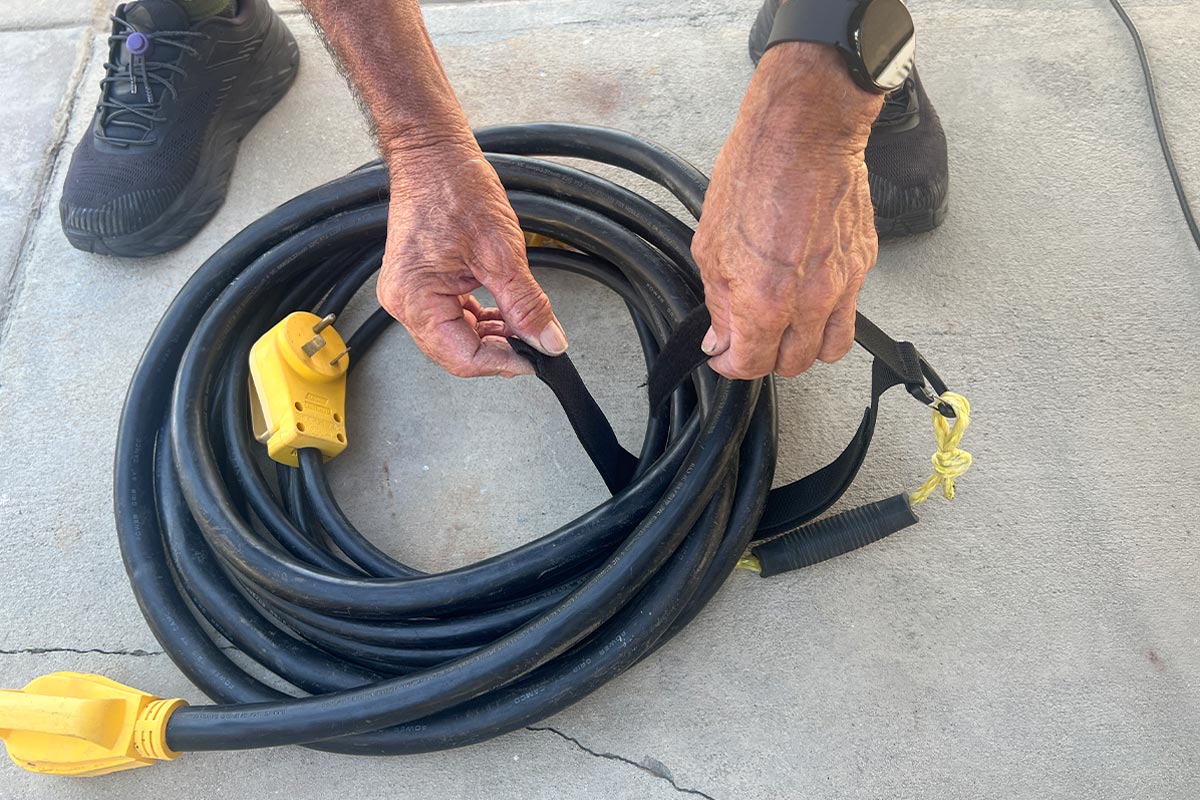 the doubled-up straps, now with the Bucket Boss handle polypropylene rope connected, is wrapped and fastened around the thick power cord roll