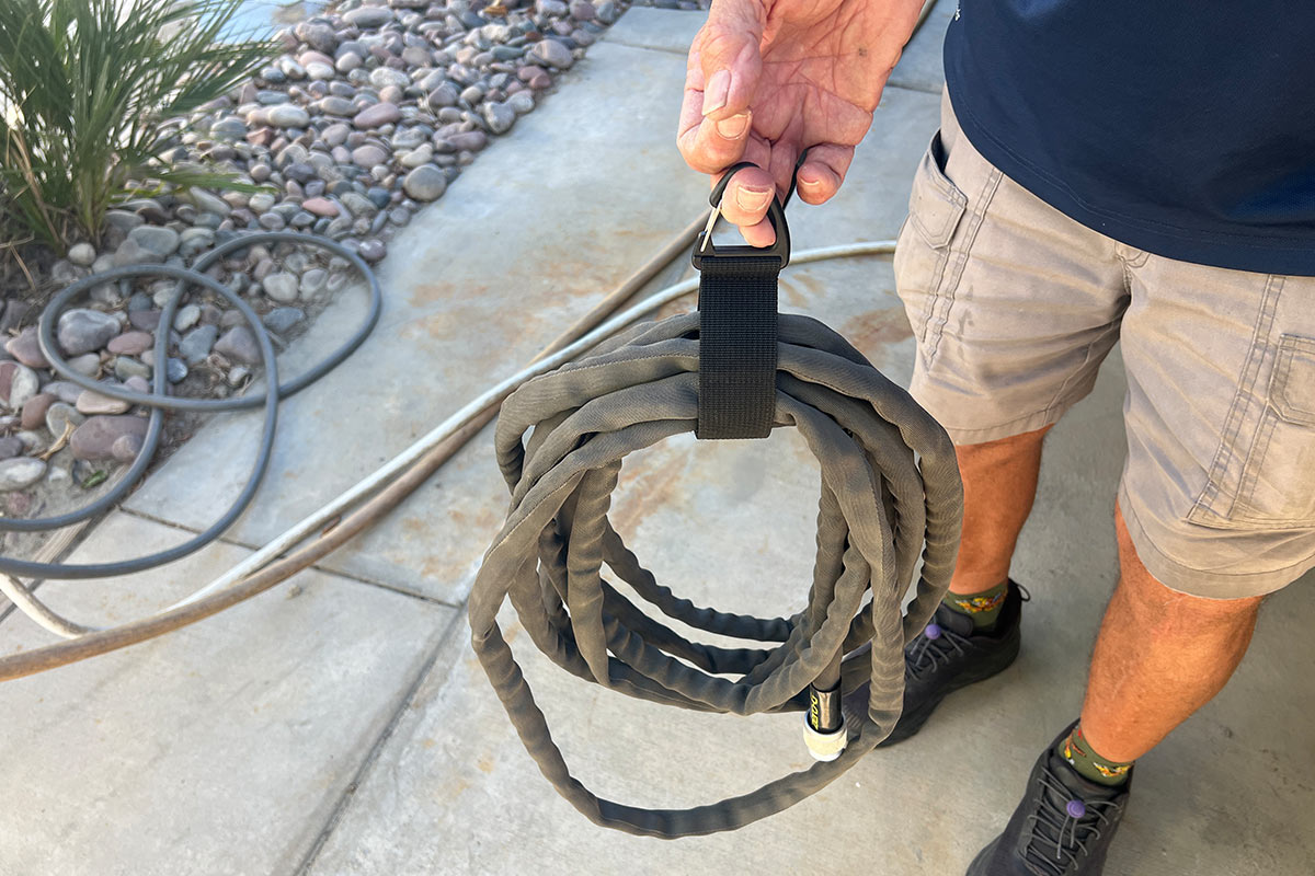 an Extension Cord Organizer strap is wrapped around a water hose