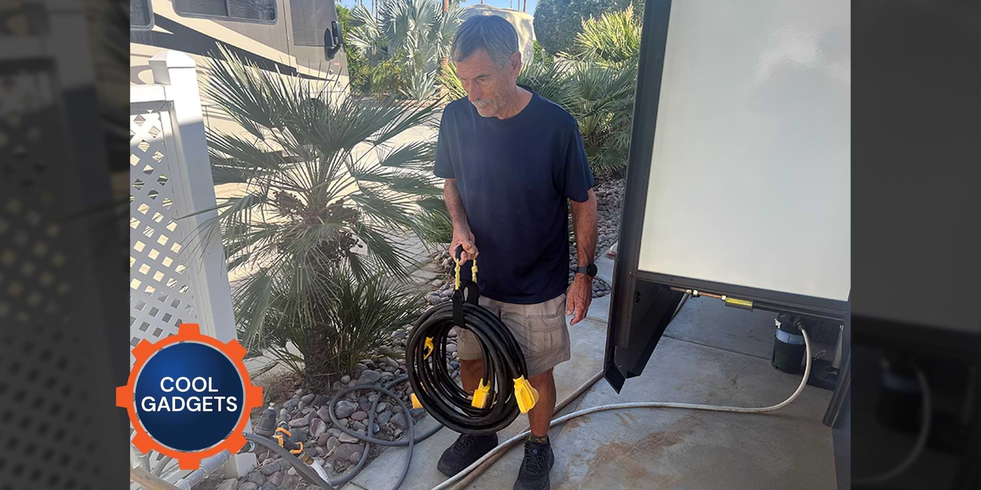a man stands beside an RV holding the handle of a strap looped around a thick power cord roll