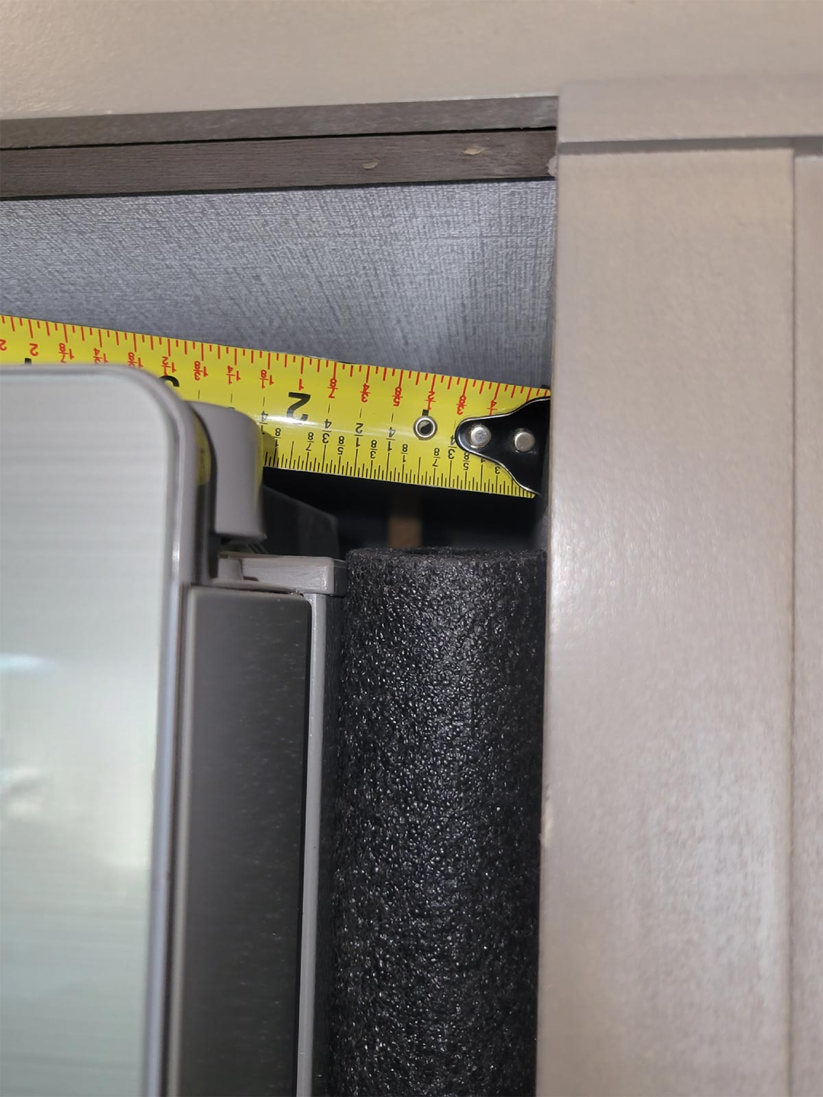 close view of a measuring tape against the top of the RV refrigerator with the Everbilt Foam Semi-Slit Polyethylene Pipe Insulation taking the place of the gap