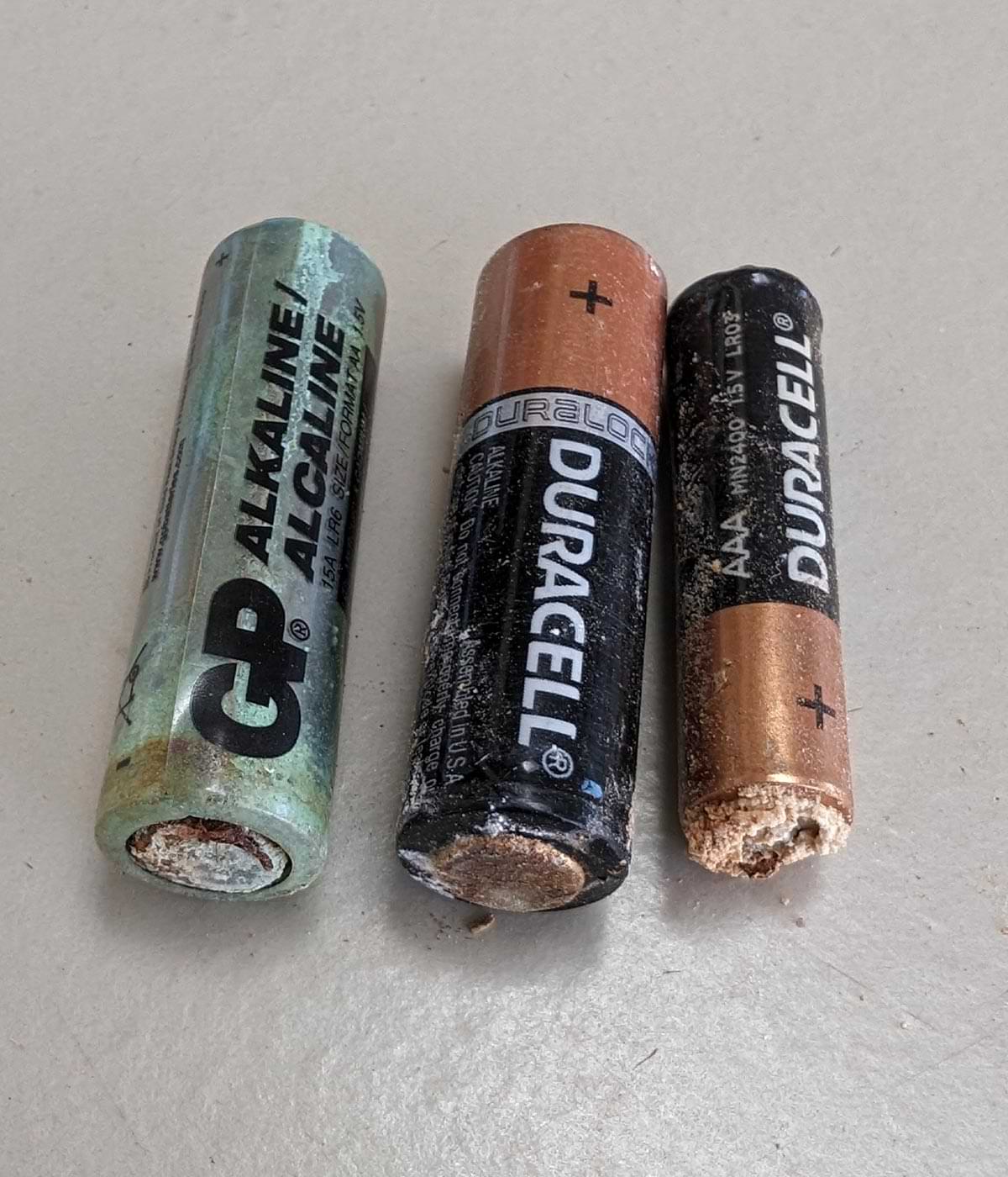 a GP and two Duracell alkaline batteries, all three in various stages of corrosion