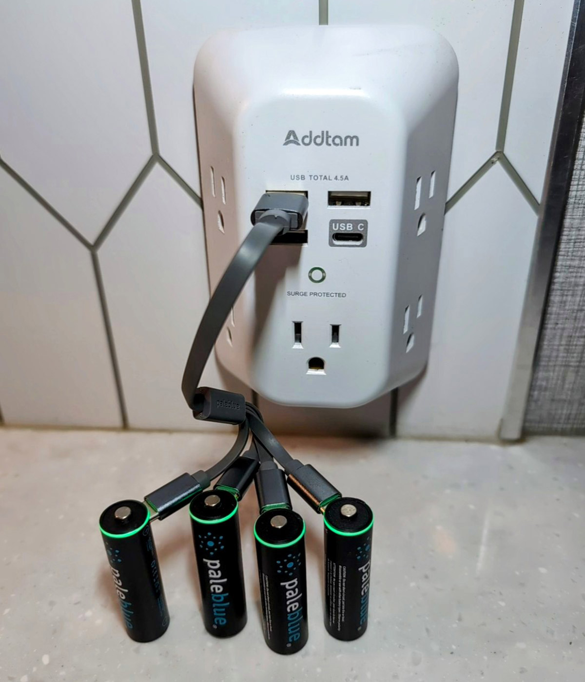 close view of four double A batteries being charged connected to an Addtam walll charger