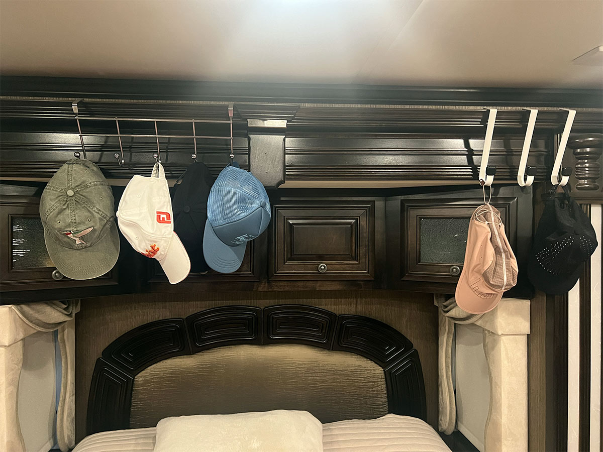 view of two over-the-door hooks hanging from the board above a master bed in an RV