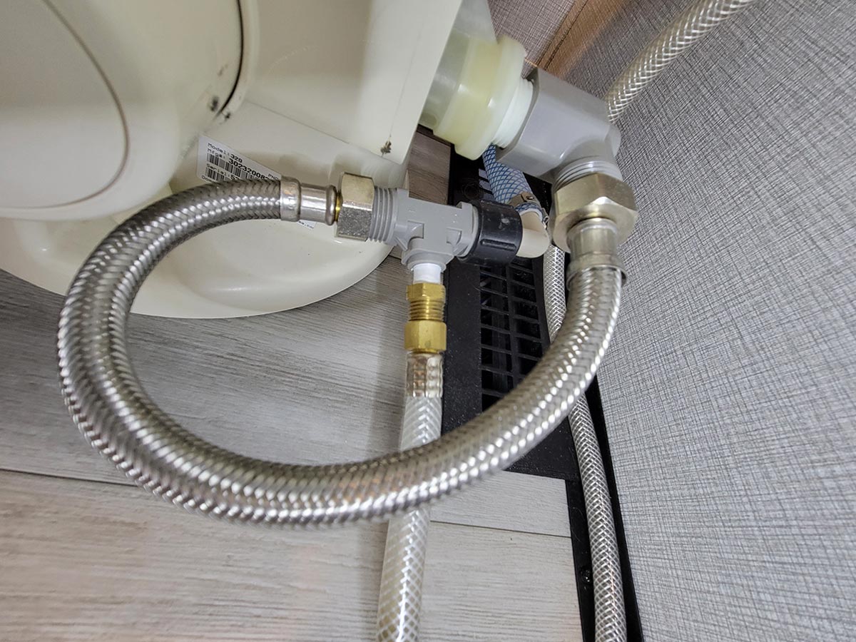 view of the durable 12-inch steel braided hose connected to the back of an RV toilet