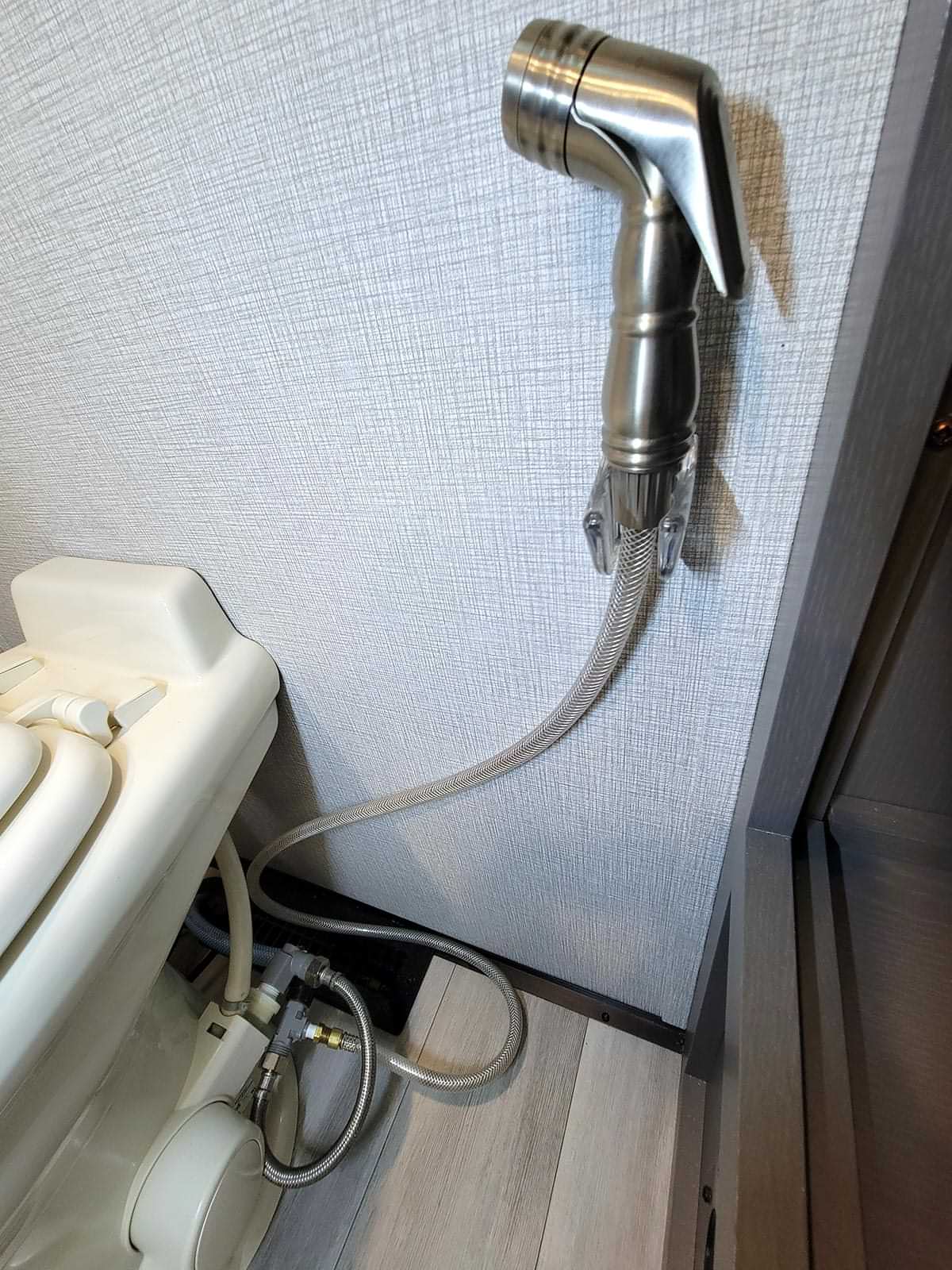 the RV toilet spray head is secured to a wall with a bracket commonly used for shower heads