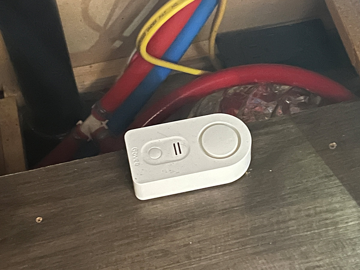 close view of a Govee water alarm sensor placed under the kitchen sink