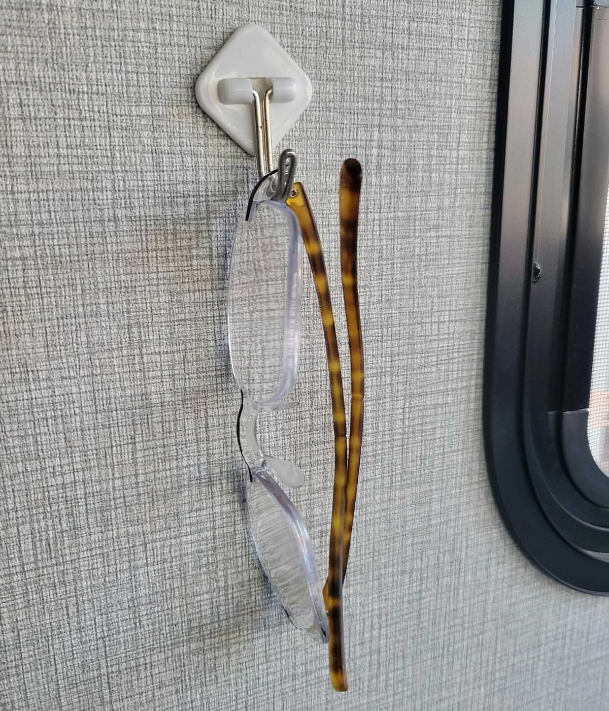 close view of a pair of glasses hanging from a generic hook with self-adhesive tape