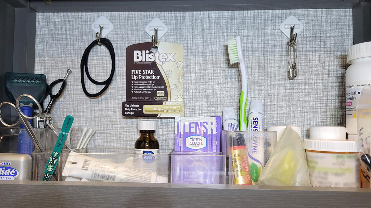 view of a medicine cabinet with hooks holding hair ties, a Blistex package and diaper pins