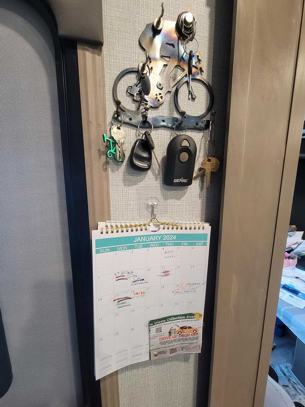 various keys hang from magnetic hooks attached to metal wall-mounted holder, below a calendar hangs from a JelKen transparent base hook