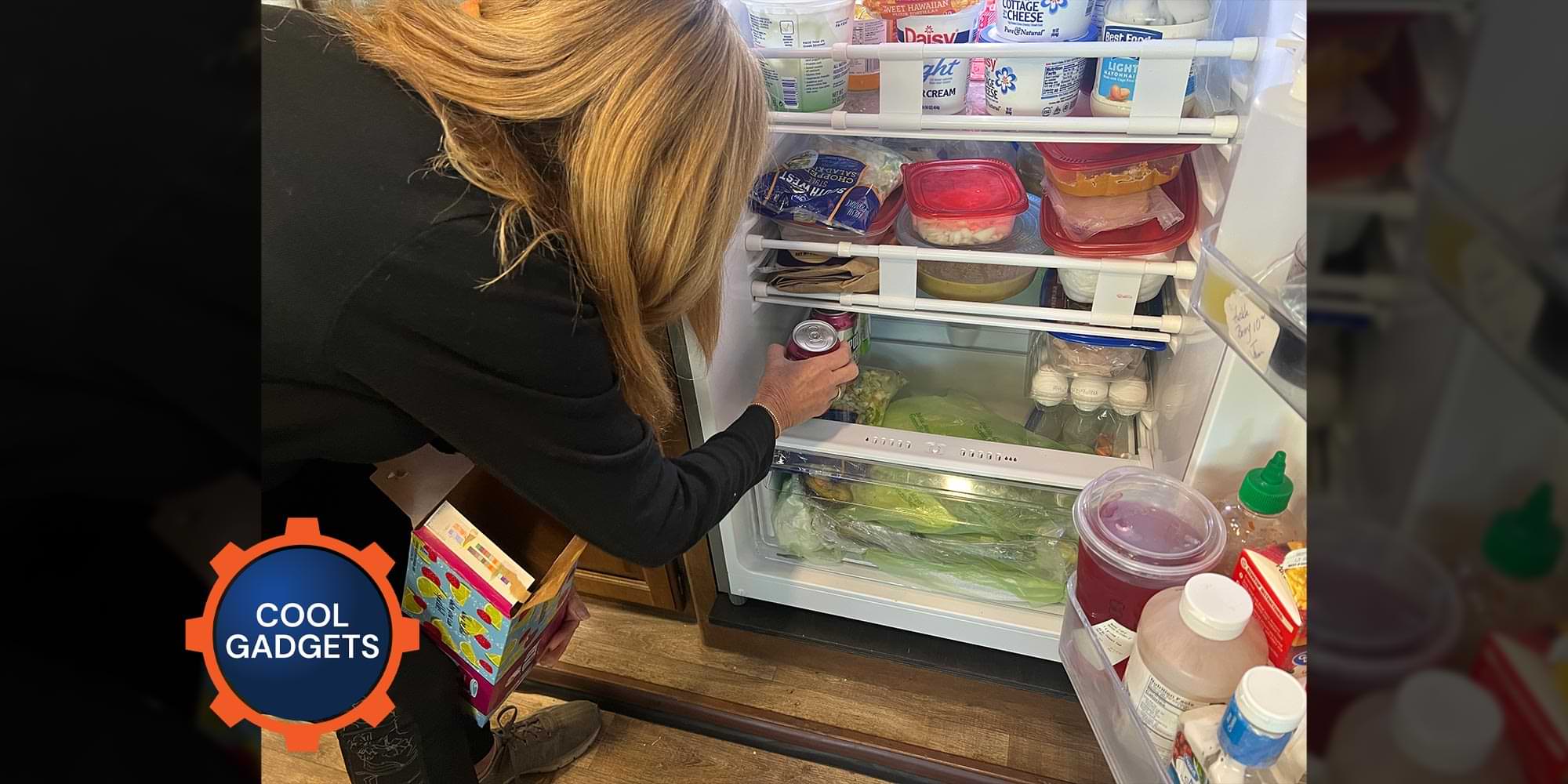 back view of a woman leaning and placing cans on the bottom shelf of an RV refrigerator
