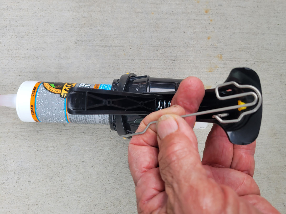 close view of a hand holding a built-in puncture tool supplied under the handle of the Siligun cartridge