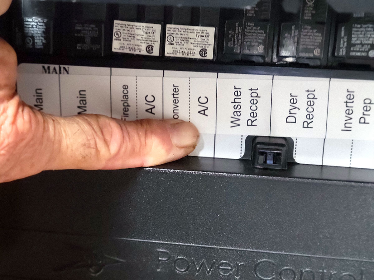 a finger points to the A/C label on the RV breaker panel