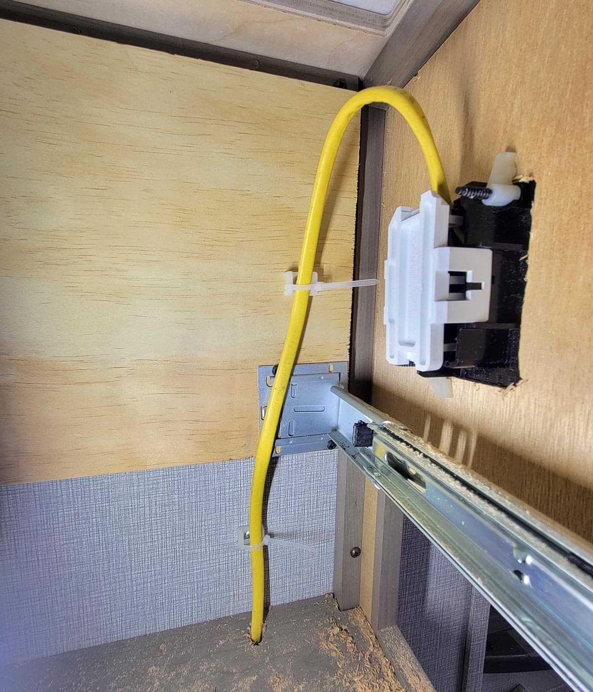 inside/back view of the outlet installed with the Romex secured tightly against the wall using small clamps