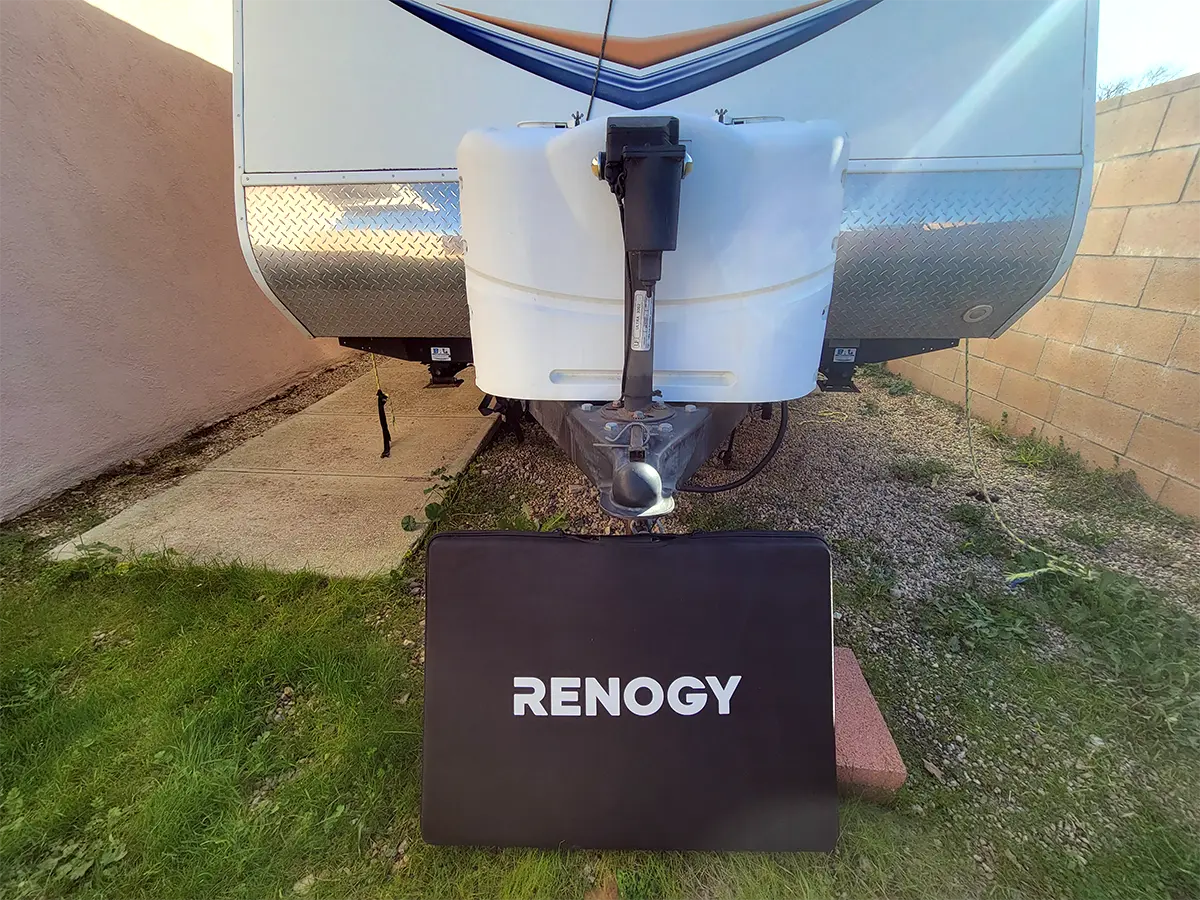 the soft, padded Renogy case placed on the ground in front of an unhitched trailer in an enclosed area