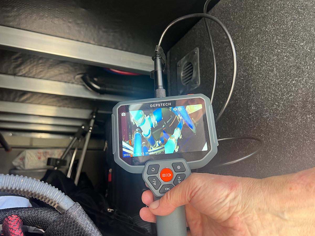 view of the Depstech DS590 endoscope screen as the camera end of the cable is routed behind the water manifold in the utility bay of an RV