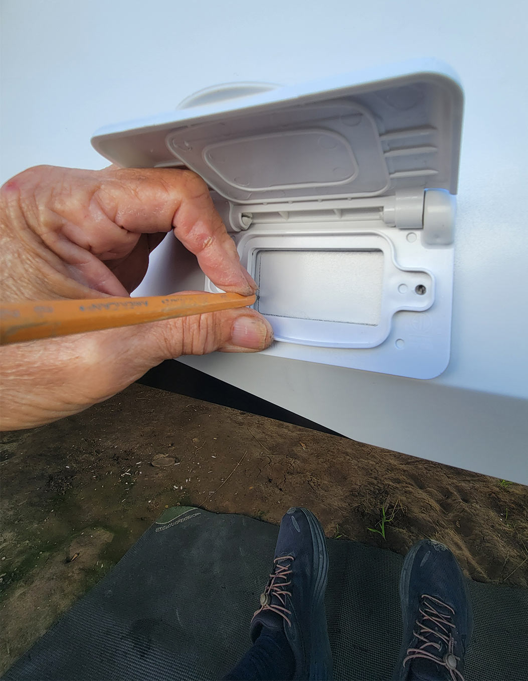 the cover plate of the new weatherproof outlet is used to create a template area to cut on the lower metal skirt of an RV