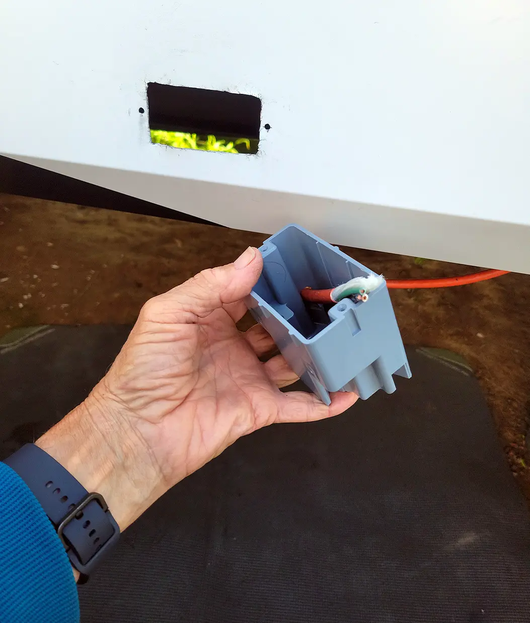 a hand hold the junction box with the extension cord cable routed