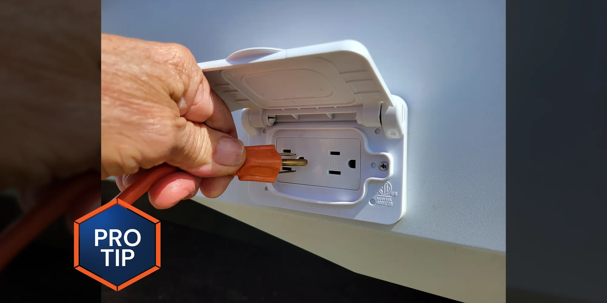 close up of a hand placing a plug in an outlet on the exterior of an RV