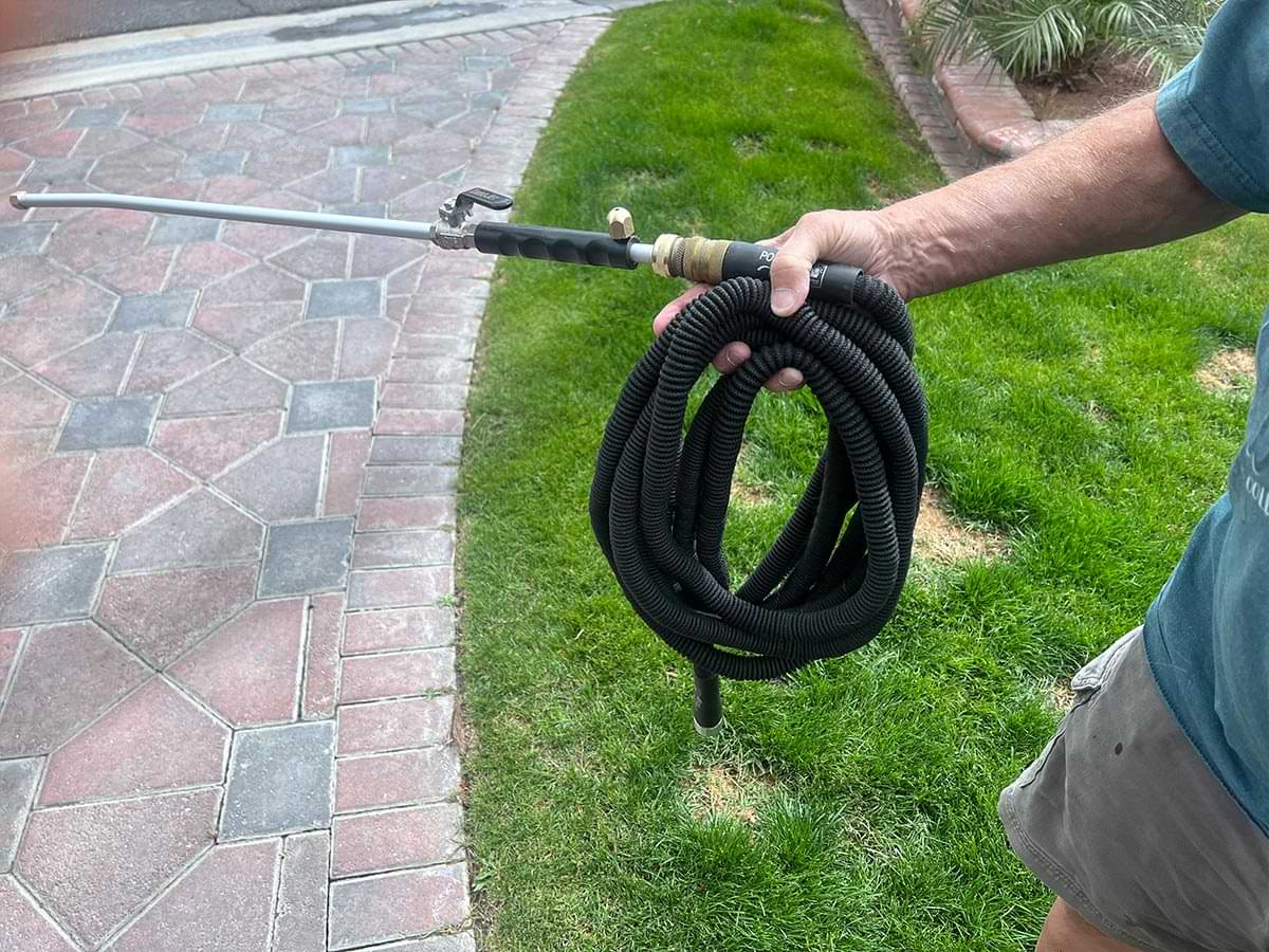 a hand holds a wound and easily handled retractable hose with the Turbo Jet Power Washer attached
