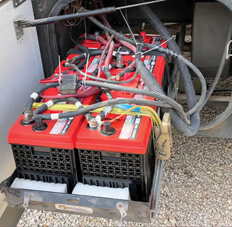 an open external compartment on an RV with a roll out tray hold red battery packs