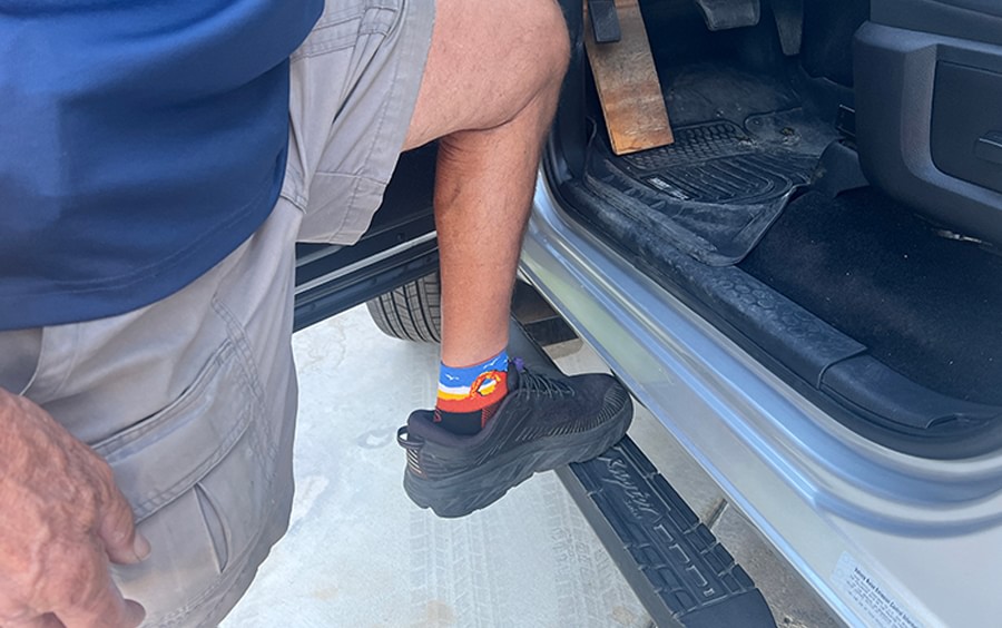 man stepping on running board of truck by door
