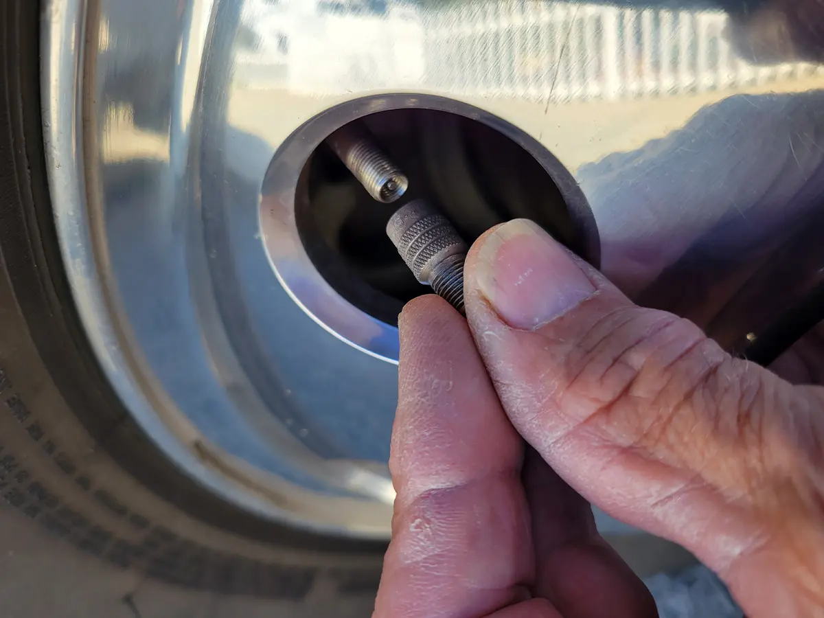 a Gator Cap is screwed onto the Schrader valve in the front wheel of a Ram dual-rear-wheel truck