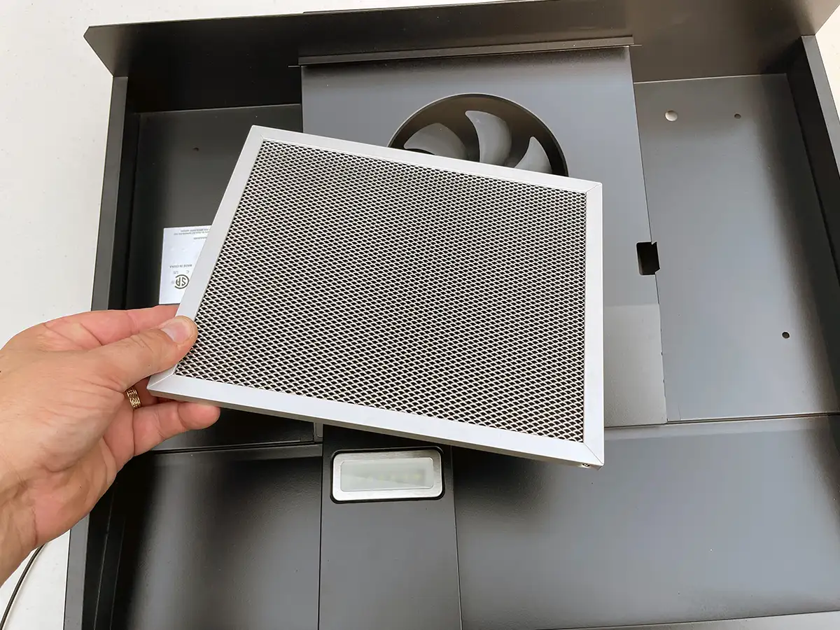 a hand holds the vent cover of a range hood