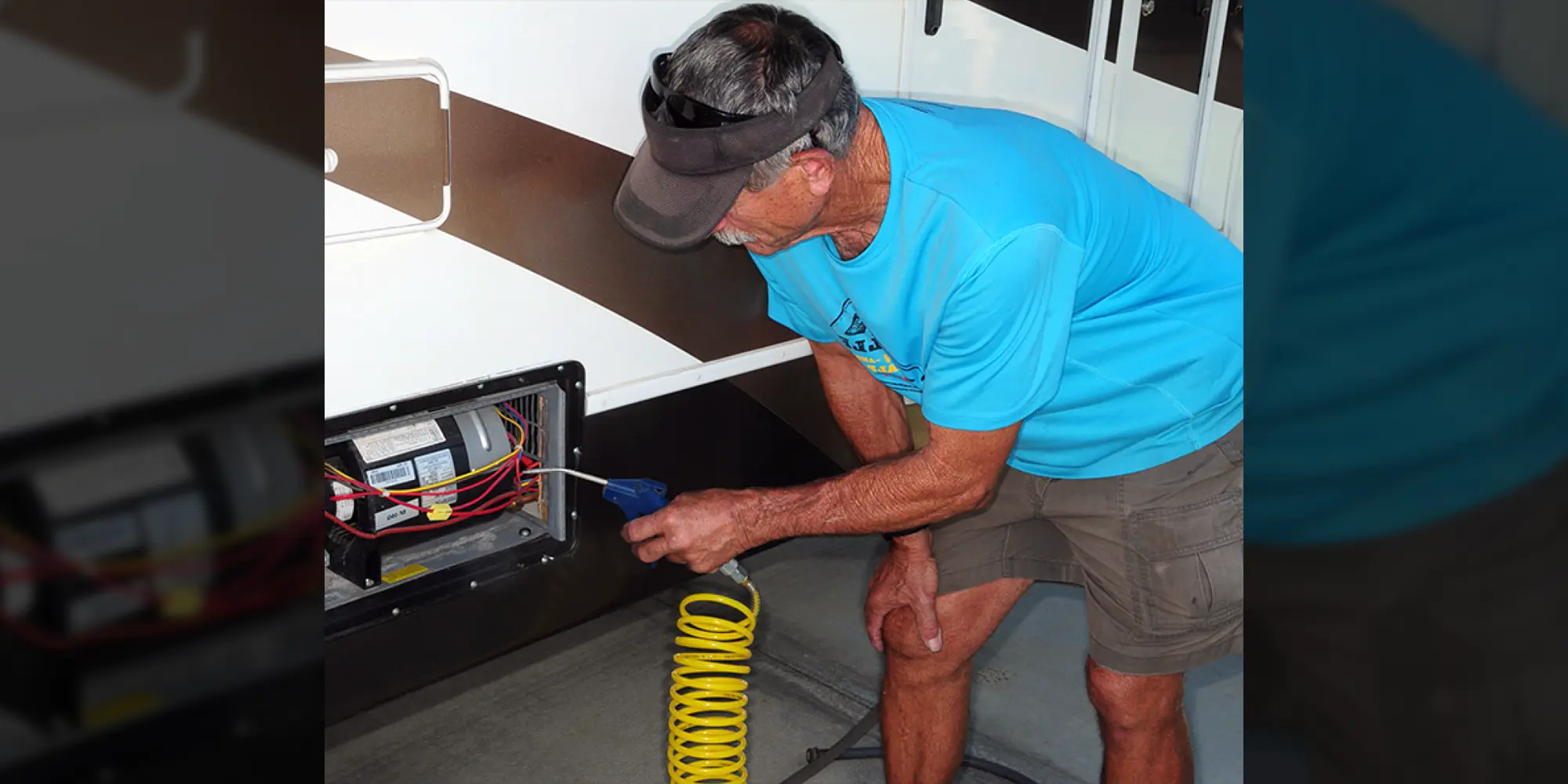 Furnace model being inspected and service by man in blue shirt, brown shorts, and brown visor.