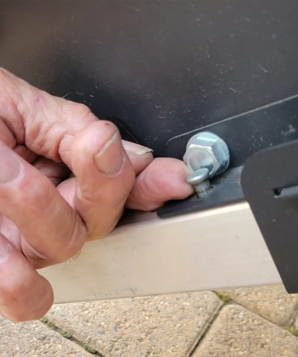 close view of an index finger attempting to remove a lipped factory pin from an RV exterior