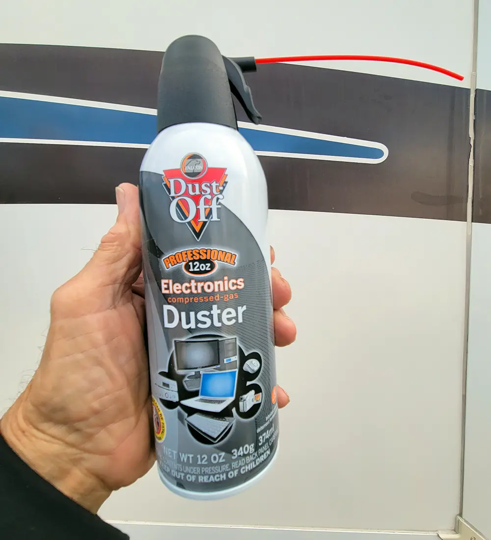 a hand holds a container of Falcon Dust-Off Electronic Duster up right in a displaying fashion