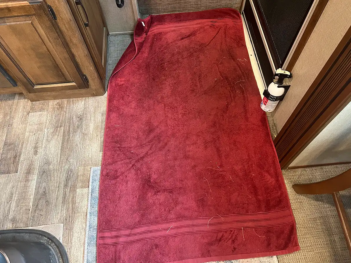 a red damp looking bath towel laid out like a mat on the floor in front of an RV entryway
